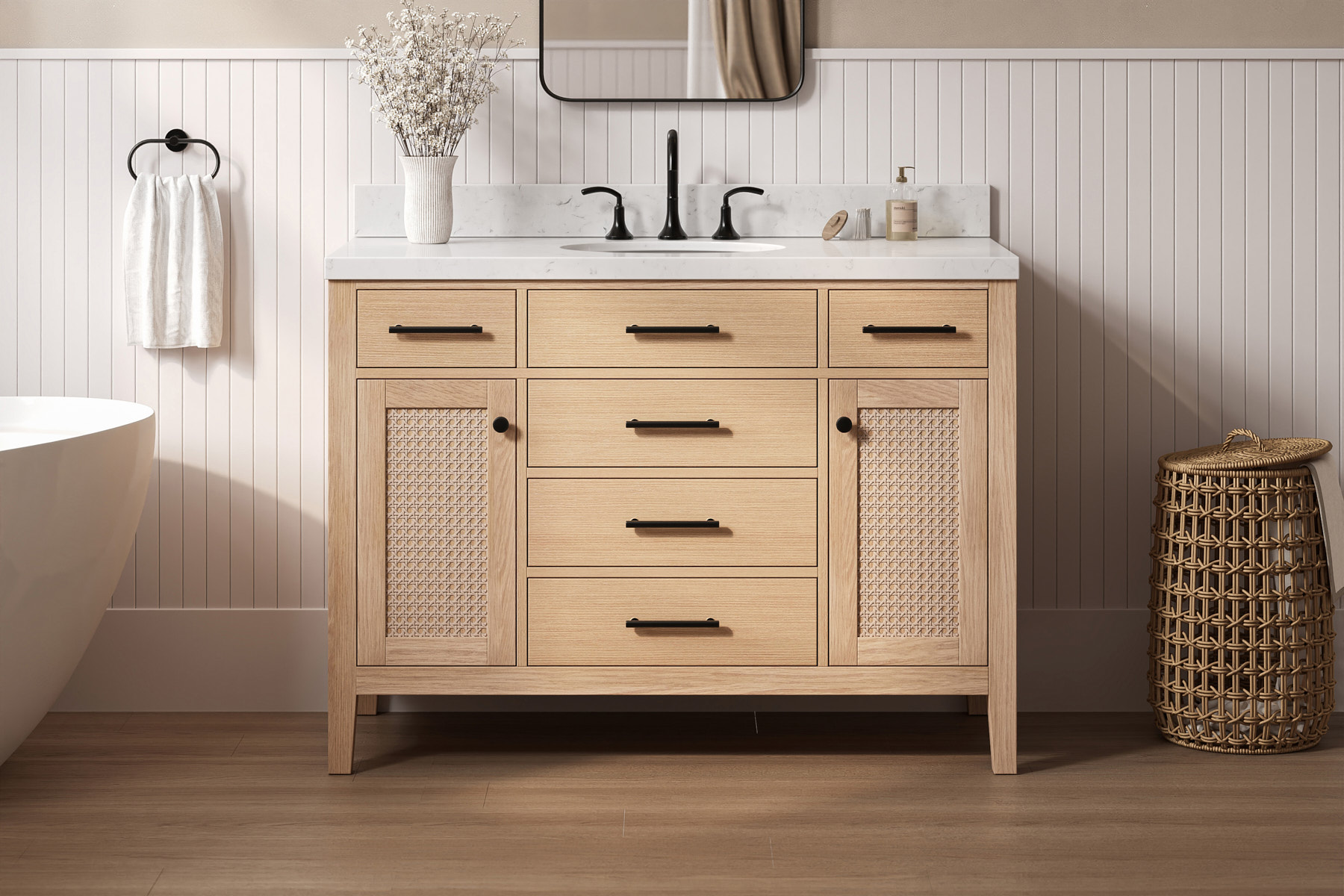 Natural oak vanity with rattan door panels, matte black hardware, and marble top, styled with soft neutral decor.